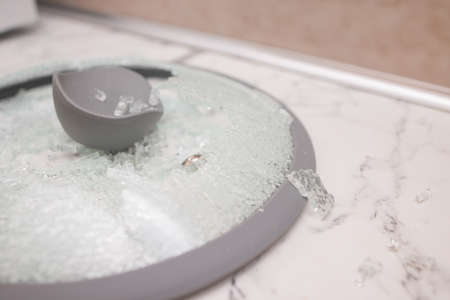 A close-up of a broken glass lid lies on a stake of tile. shards of glass shine. soft focus, top view.の写真素材