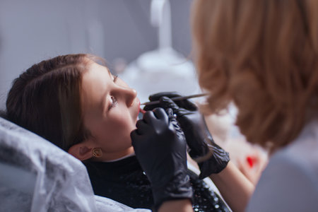 Caucasian young child girl sitting in medical chair while dentist fixing teeth at dental clinic using dental tools instruments, close-up photo of face. professional medical specialist.の写真素材