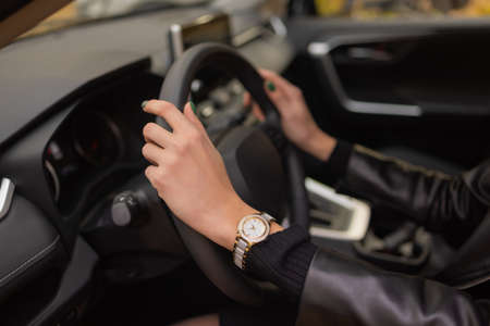 womans hands holding on to the wheel of a new car in the showroom.の写真素材