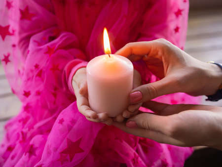Closeup childrens hands hold a candle in the church during prayer.の写真素材