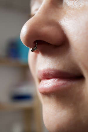 Closeup of a young womans visage with piercing septum hanging from her nose.の写真素材