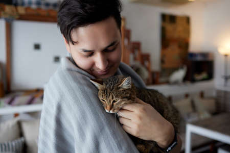 Young man in t shirt holding a cat.の写真素材