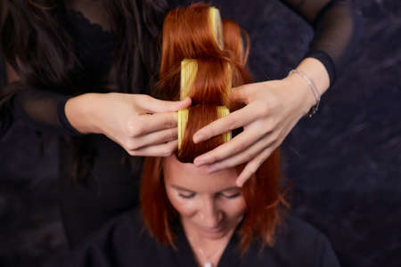 Closeup of red hair during hair dressing with curler.の写真素材