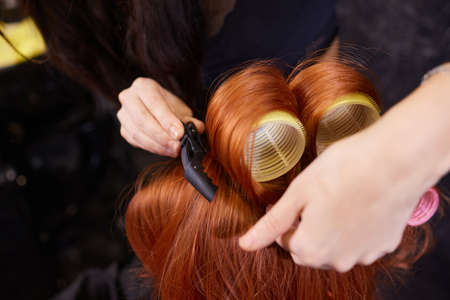 Closeup of red hair during hair dressing with curler.の写真素材