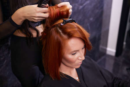 Closeup of red hair during hair dressing with curler.の写真素材