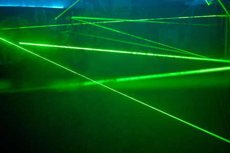 Bright green neon laser lights illuminate the darkness creating lines and triangle shapes in sci-fi effect.の写真素材