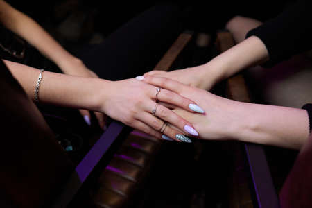 Cropped shot of young couple holding hands while sitting together. Focus on hands.