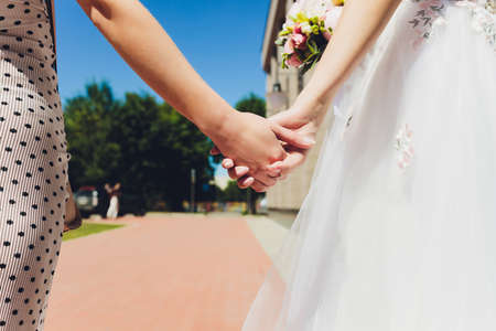 Concept of love between young women : Two women standing behind their backs holding hands together in the rainy season.の写真素材