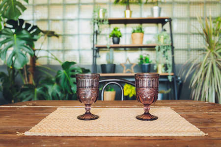 Vintage glasses of gray-blue color stand on a table illuminated by purple light with yellow highlights, on a blurry background in dark lighting.の写真素材