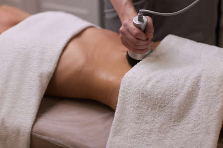 procedure removing cellulite on female abdomen, cavitation belly massage. Ultrasonic massage for weight loss. Correction of female figure without surgical intervention. Closeup of the tummy.の写真素材
