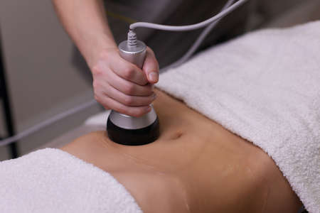procedure removing cellulite on female abdomen, cavitation belly massage. Ultrasonic massage for weight loss. Correction of female figure without surgical intervention. Closeup of the tummy.の写真素材