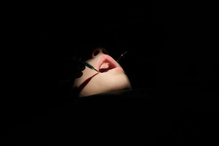 The dentist examines teeth of the child with a microscope. Professional dental equipment.