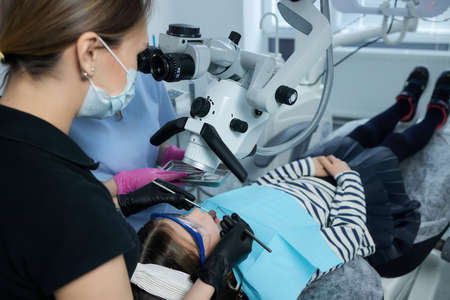 The dentist examines teeth of the child with a microscope. Professional dental equipment.の写真素材