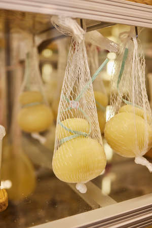 Delicious fresh Caciocavallo and Scamorza cheese hanging. Italian cheeses close up. The cheeses are...