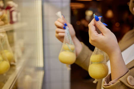 Delicious fresh Caciocavallo and Scamorza cheese hanging. Italian cheeses close up. The cheeses are...