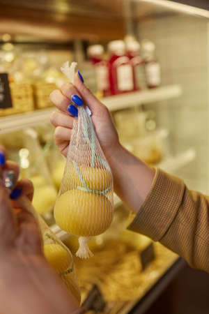 Delicious fresh Caciocavallo and Scamorza cheese hanging. Italian cheeses close up. The cheeses are handmade. The production of cheese.の写真素材