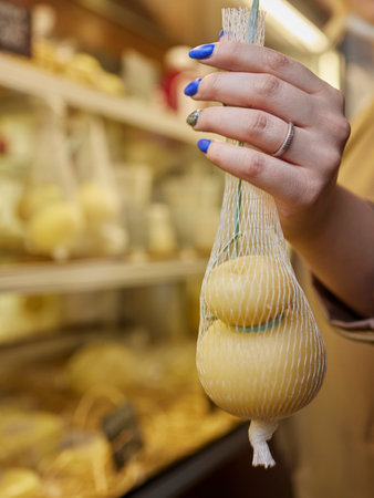Delicious fresh Caciocavallo and Scamorza cheese hanging. Italian cheeses close up. The cheeses are handmade. The production of cheese.の写真素材