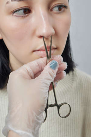 Closeup of a young womans visage with piercing septum hanging from her nose.