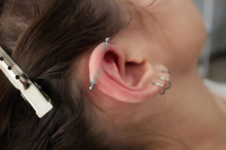 Stretched lobe piercing, grunge concept. Pierced woman ear with black plug tunnel. industrial and...