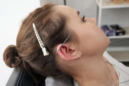 Stretched lobe piercing, grunge concept. Pierced woman ear with black plug tunnel. industrial and...