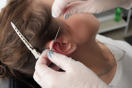 Stretched lobe piercing, grunge concept. Pierced woman ear with black plug tunnel. industrial and...