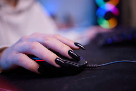 Close-up hands shot asia girl gamer use keyboard and mouse controller play video game with neon light computer in desk at home. Online esport streaming game online, Home quarantine activity concept.の写真素材