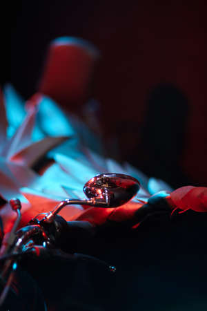 Rear-view mirror reflection of a modern biker sat on classic motorcycle. Outdoor portrait and urban...