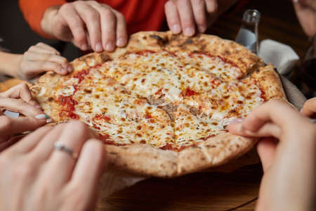 Close up cropped portrait of young handsome man with beard eating tasty slice of pizza.の写真素材