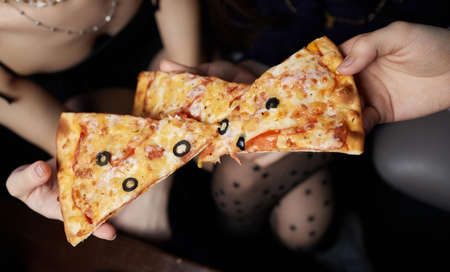 Close up cropped portrait of young handsome man with beard eating tasty slice of pizza.