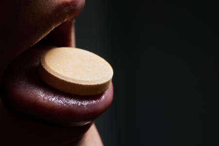 Man taking pill, mouth open with tongue sticking out.の写真素材