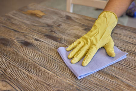 A mans hand in medical glove wipes the table with napkin. Background waiter in an apron in blur. Surface treatment.の写真素材