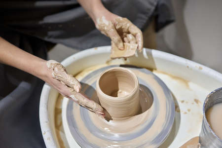 Close up shot of hands of crafts people, working with clay in pottery studio.の写真素材