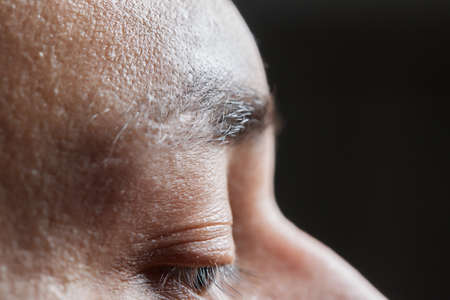 Professional barber doing threading procedure and correcting shape of eyebrows to young male client...