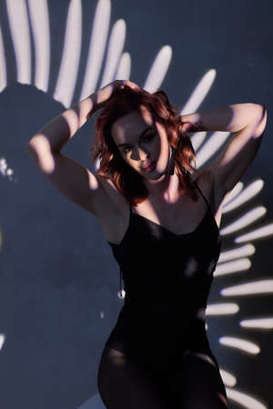 woman in black bodysuit in the backlight of a photo studio.