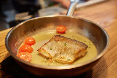 Dish of fish fillet with salad on dripping pan close up.