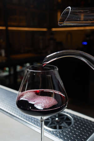 Sommelier man pours red wine into decanter for aeration of taste and aroma.の写真素材