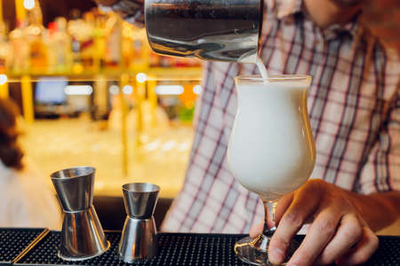 Close up shot of bartender hand pouring Cream mocktail in a glass from shaker.の写真素材