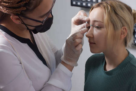 Nose Bridge Piercing Professional holding the jewel of piercing day just before screw the ball.の写真素材