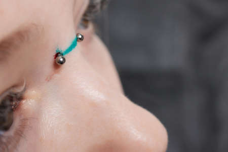Nose Bridge Piercing Professional holding the jewel of piercing day just before screw the ball.