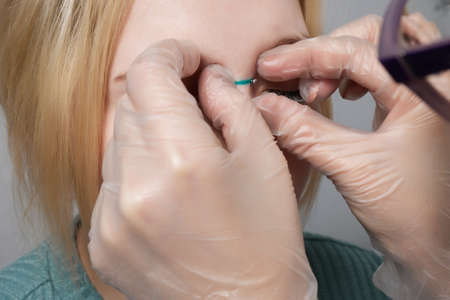 Nose Bridge Piercing Professional holding the jewel of piercing day just before screw the ball.