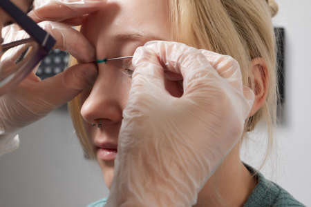 Nose Bridge Piercing Professional holding the jewel of piercing day just before screw the ball.