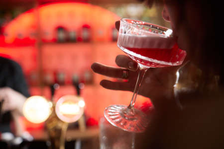Low angle closeup of a gourmet mixed drink cocktail of sweet pink lemonade vodka and gin martini,...