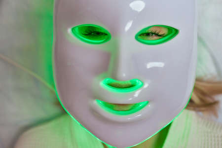 LED light anti-aging mask for facial skin care in a spa slow motion. A woman lies on a couch in a special mask. Modern technologies of beauty and health.の写真素材