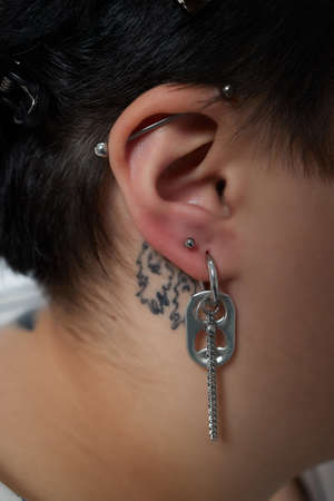 A beautician makes a puncture of the earlobe with a disposable device in a beauty salon. Ear piercing lobe.の写真素材