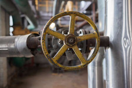Close-up at pipeline valve which is using to control production process in the oil refinery plant. Selective focus at the valve handle wheel, Heavy industrial object photo.の写真素材