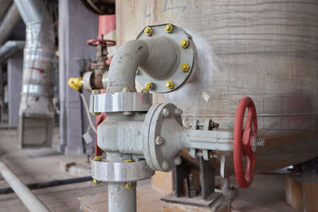 Close-up at pipeline valve which is using to control production process in the oil refinery plant. Selective focus at the valve handle wheel, Heavy industrial object photo.の写真素材