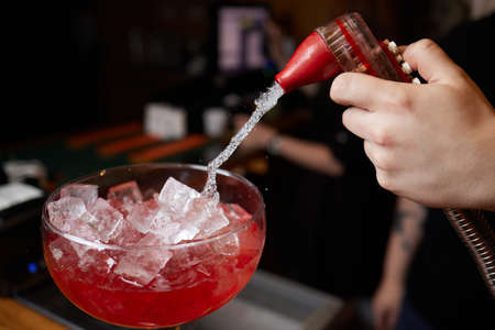 Bartender is making cocktail at bar counter at night club, Close Up. Concept about service and beverages.の写真素材