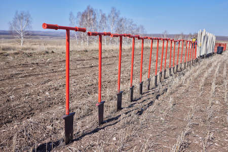 Rack with shovels near an arid field before tree planting.