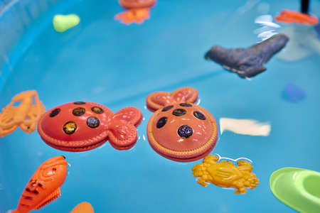 Multicolored plastic toy fish in pool for childrens fishing, concept game.