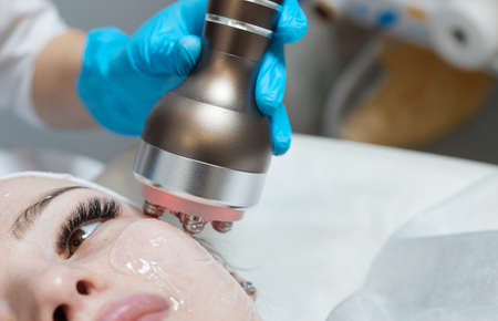 LED light anti-aging mask for facial skin care in a spa slow motion. A woman lies on a couch in a...